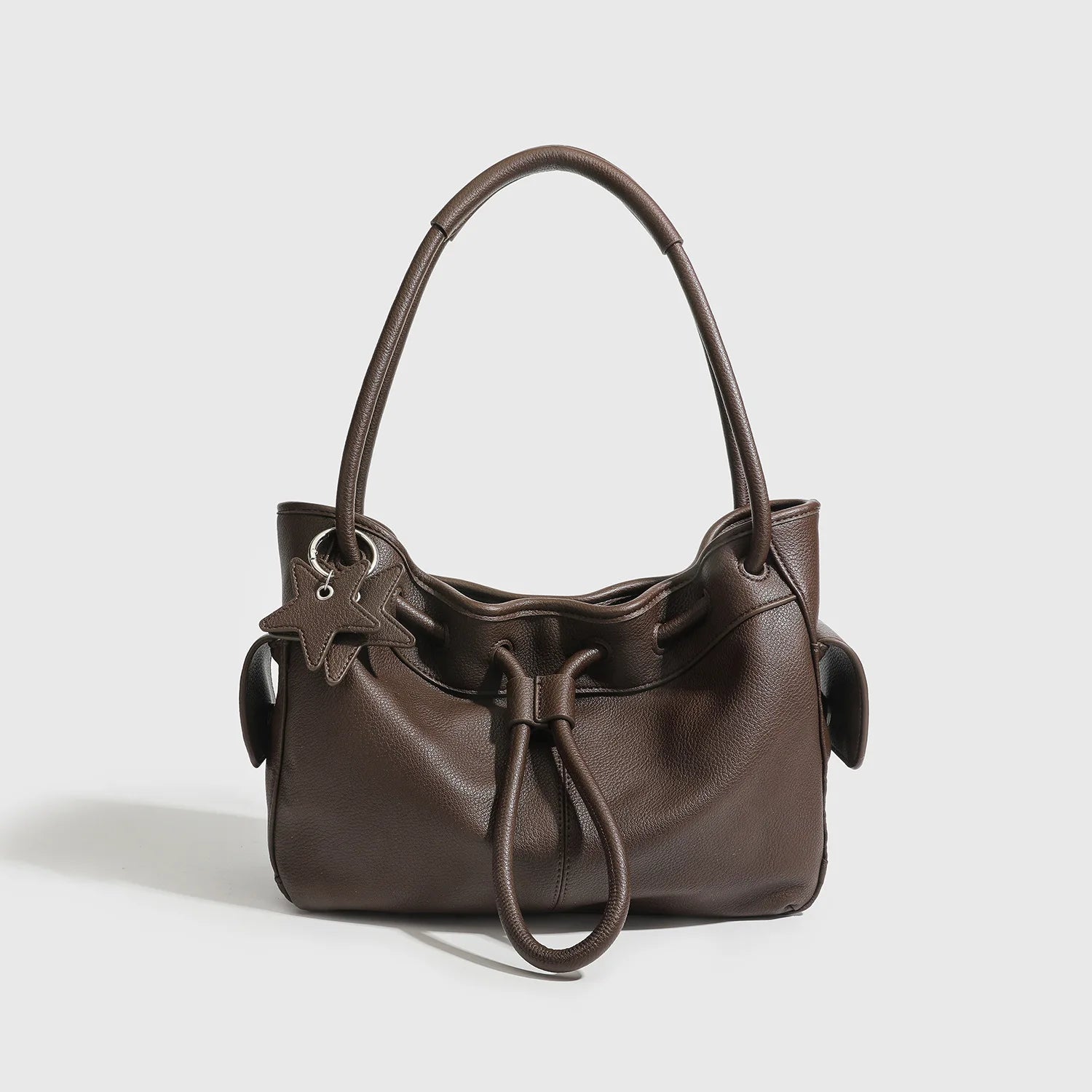 Dark brown leather underarm shoulder bag with a drawstring closure, star charm, and spacious design for commuting.