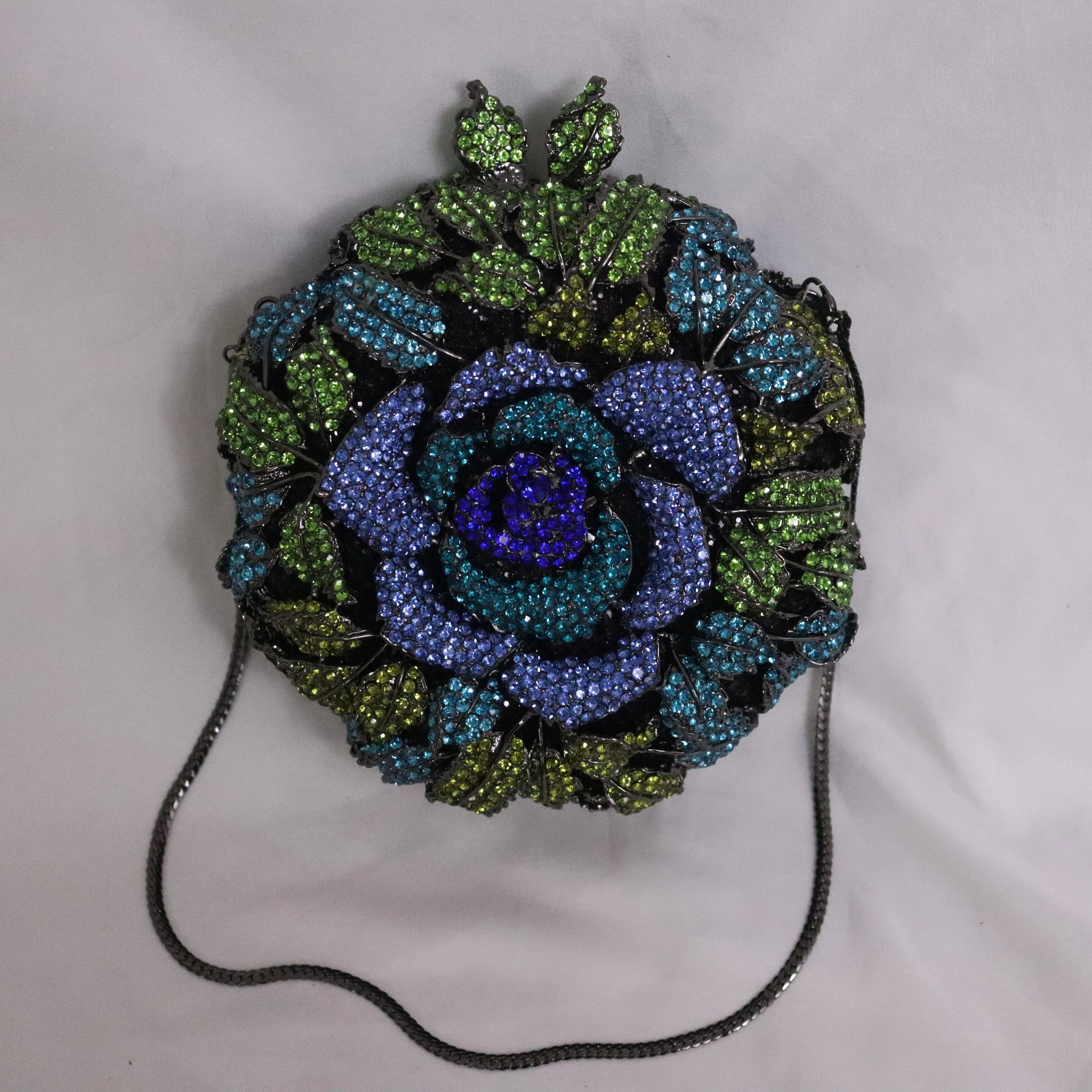 Designer handbag: Round metal evening clutch with blue and green crystal rose floral pattern and chain shoulder strap.