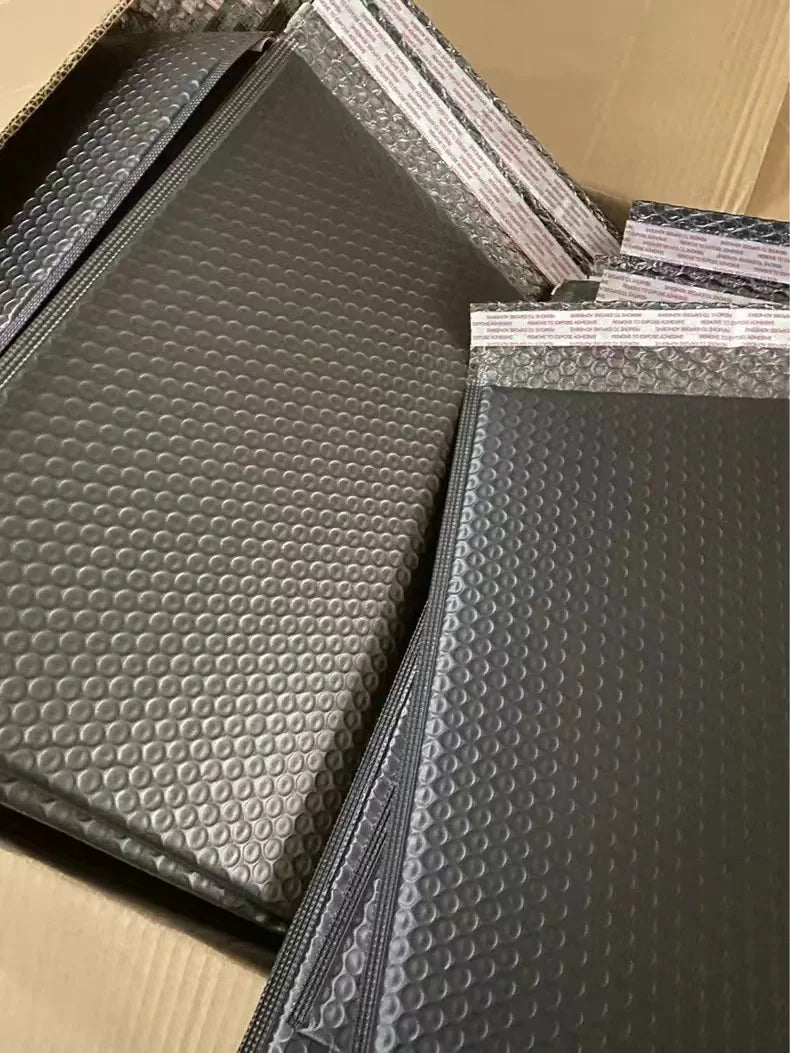 Stacked dark gray padded bubble mailer envelopes, opaque, tear-resistant