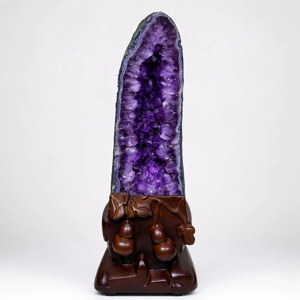Tall amethyst geode crystal cluster with purple interior on carved wooden base