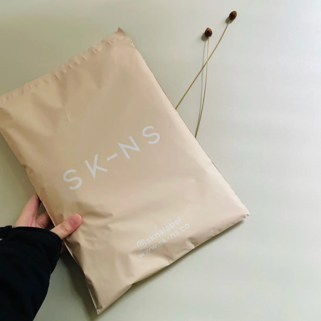 Beige poly mailer shipping bag with white 'SKINS' logo text