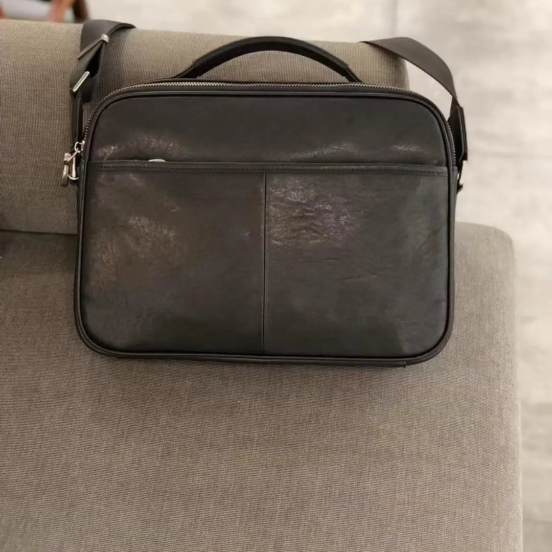 Vintage dark brown cowhide leather messenger bag with top handle, adjustable shoulder strap, and front zipper pocket.