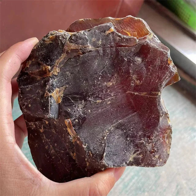 Raw amber gemstone chunk with rough, jagged surface held in a hand