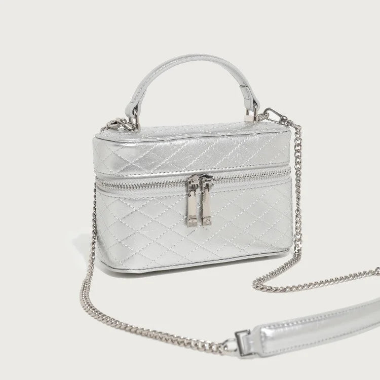 Metallic silver quilted genuine leather box trunk bag with top handle, double zipper, and detachable chain strap.