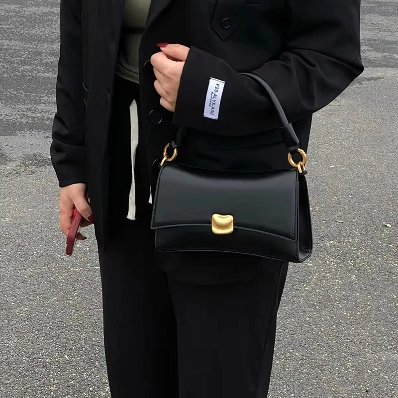 Black designer square underarm handbag with gold magnetic clasp, two straps, and smooth PU leather finish.
