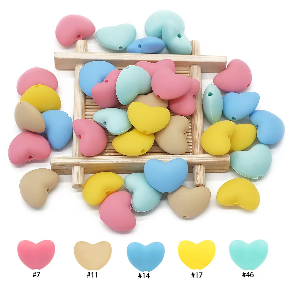 Colorful heart-shaped silicone beads for baby teething toys, available in pink, blue, yellow, and beige.
