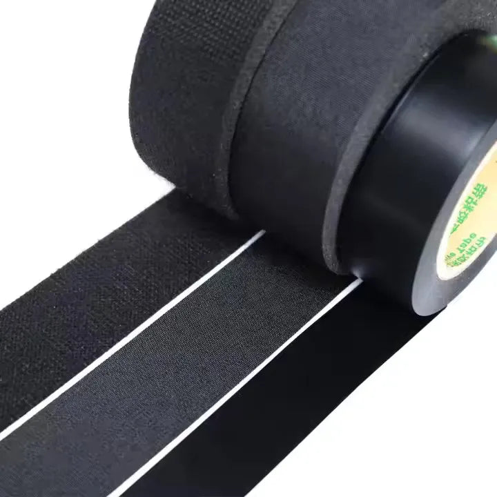 Close-up of black wire harness tape roll and textured fabric surface