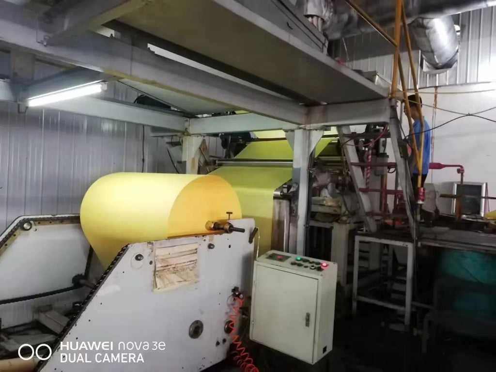 Yellow masking tape jumbo roll on industrial machine feed unit