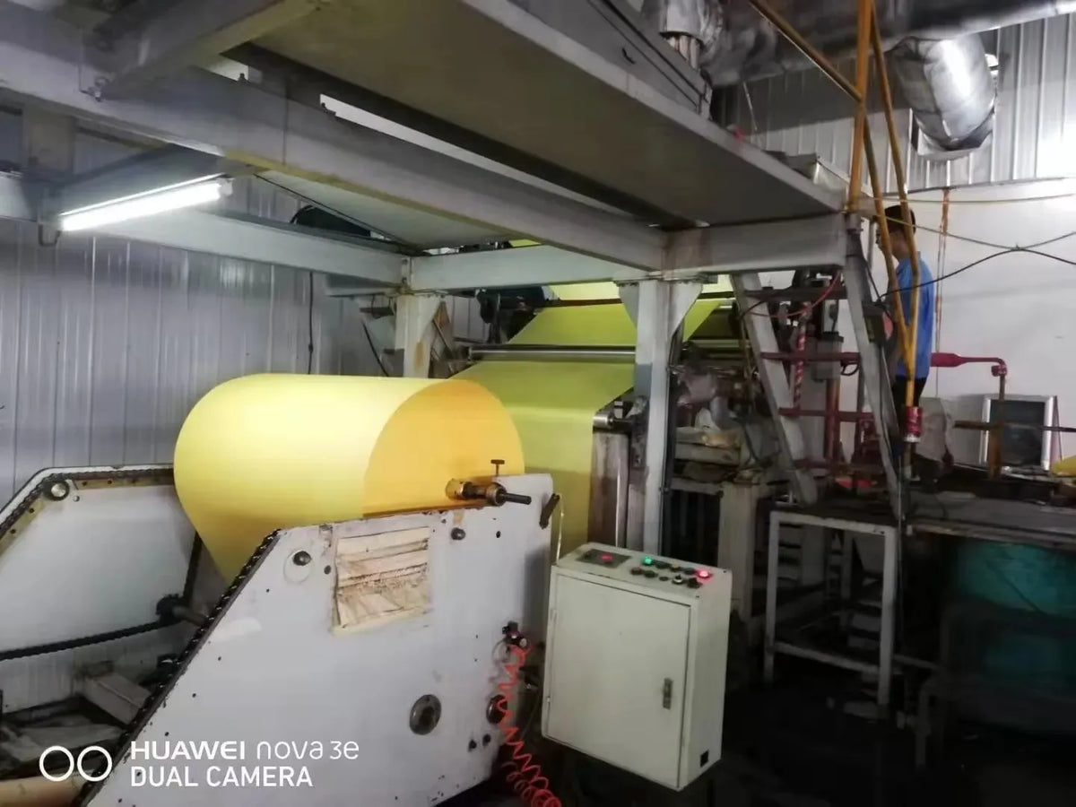 Yellow masking tape jumbo roll on industrial machine feed unit