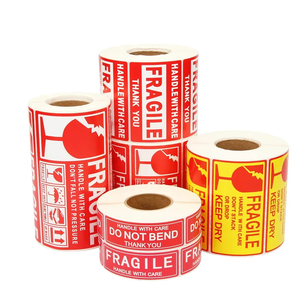 Fragile shipping warning label rolls on white backing, red and white icons and text