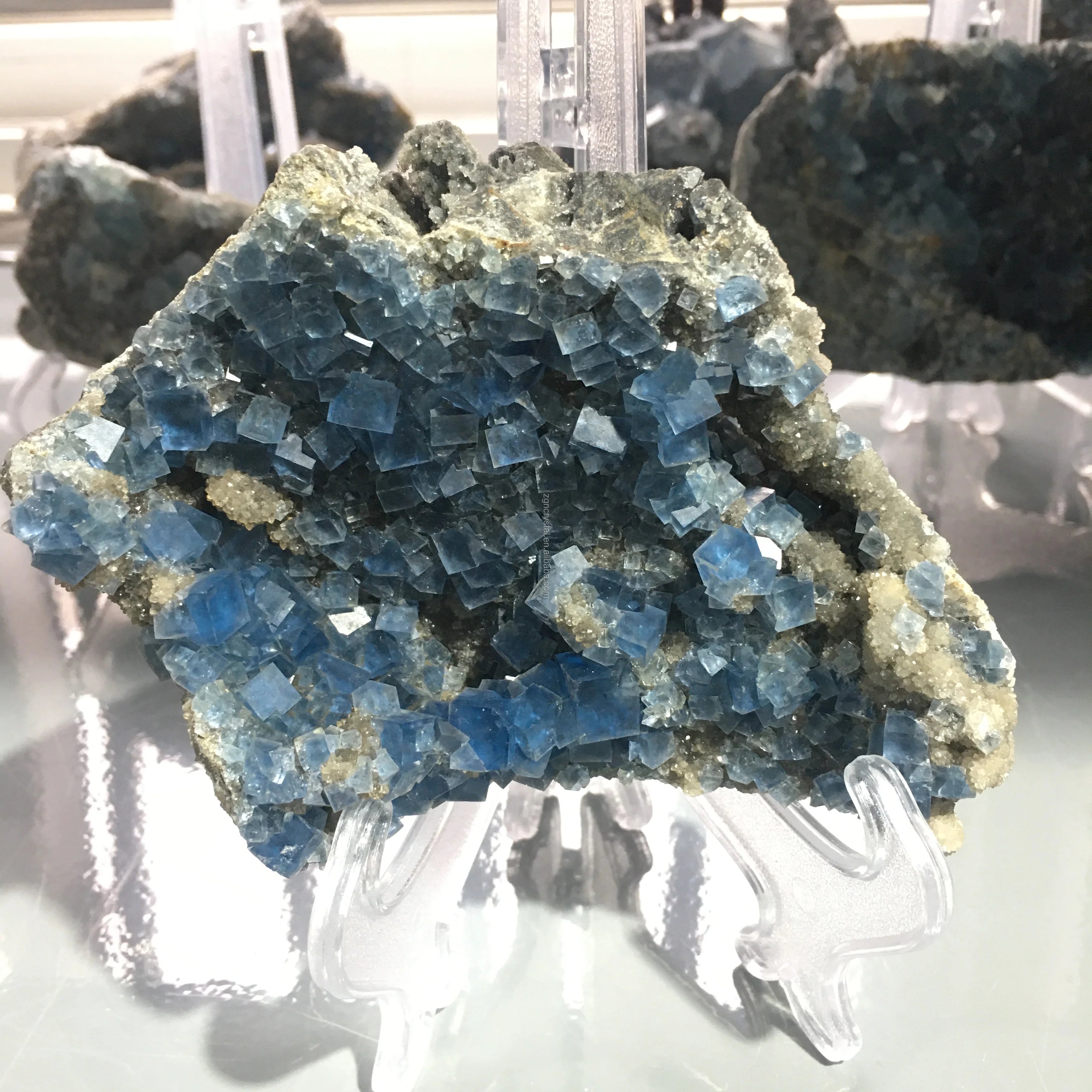 Blue fluorite crystal cluster on clear stand with rough stone matrix