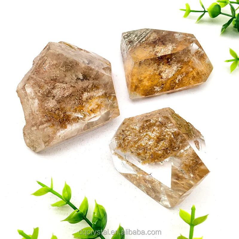 Three polished phantom quartz crystals with clear bases and golden-brown streaks