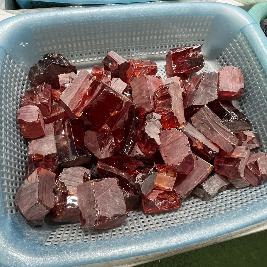 Loose red and clear rough cubic zirconia pieces in metal tray, uncut faceted pile