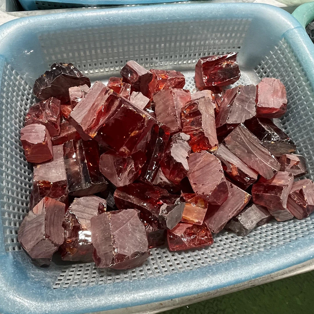 Loose red and clear rough cubic zirconia pieces in metal tray, uncut faceted pile