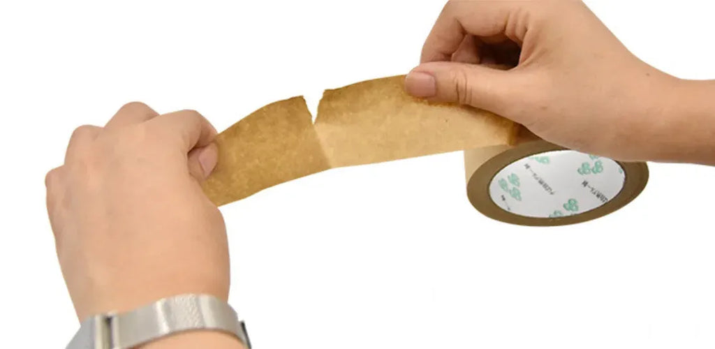 Hands applying water-activated kraft paper packing tape on brown carton edge