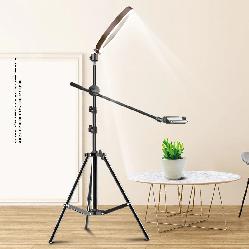 Black metal ring light on an adjustable tripod stand with a boom arm phone holder for overhead filming and photography.