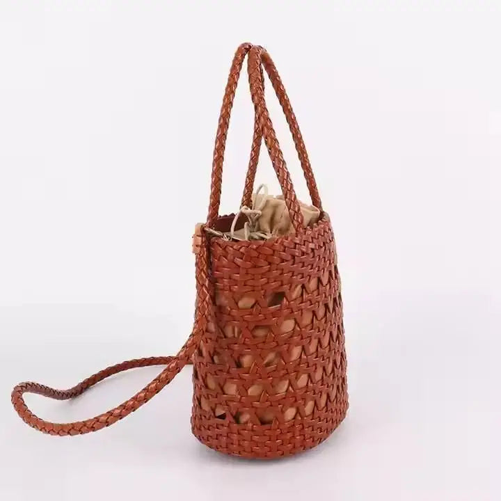 Brown handwoven leather bucket bag with cross-weave cannage design, drawstring interior, and braided carry handles.