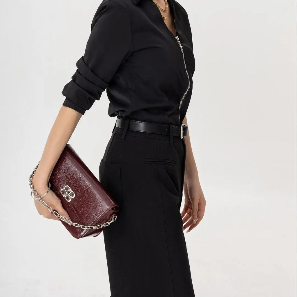 JACK CAPTAIN burgundy leather designer clutch with silver chain strap and front metal logo closure.