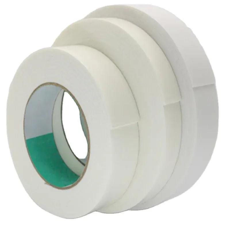 White masking tape rolls stacked, with adhesive strip edges visible