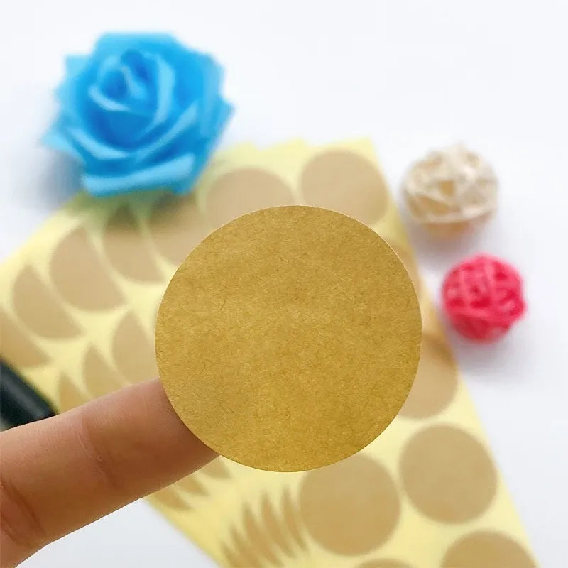 Round blank kraft paper sticker held by hand, matte writable surface