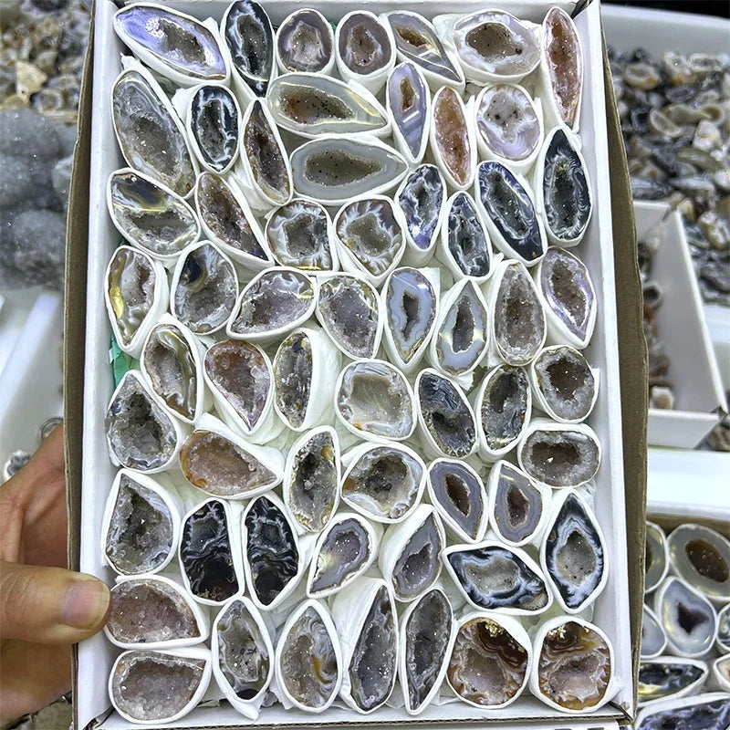 Agate geode crystal slices in a gift box held open, assorted dark gray stones