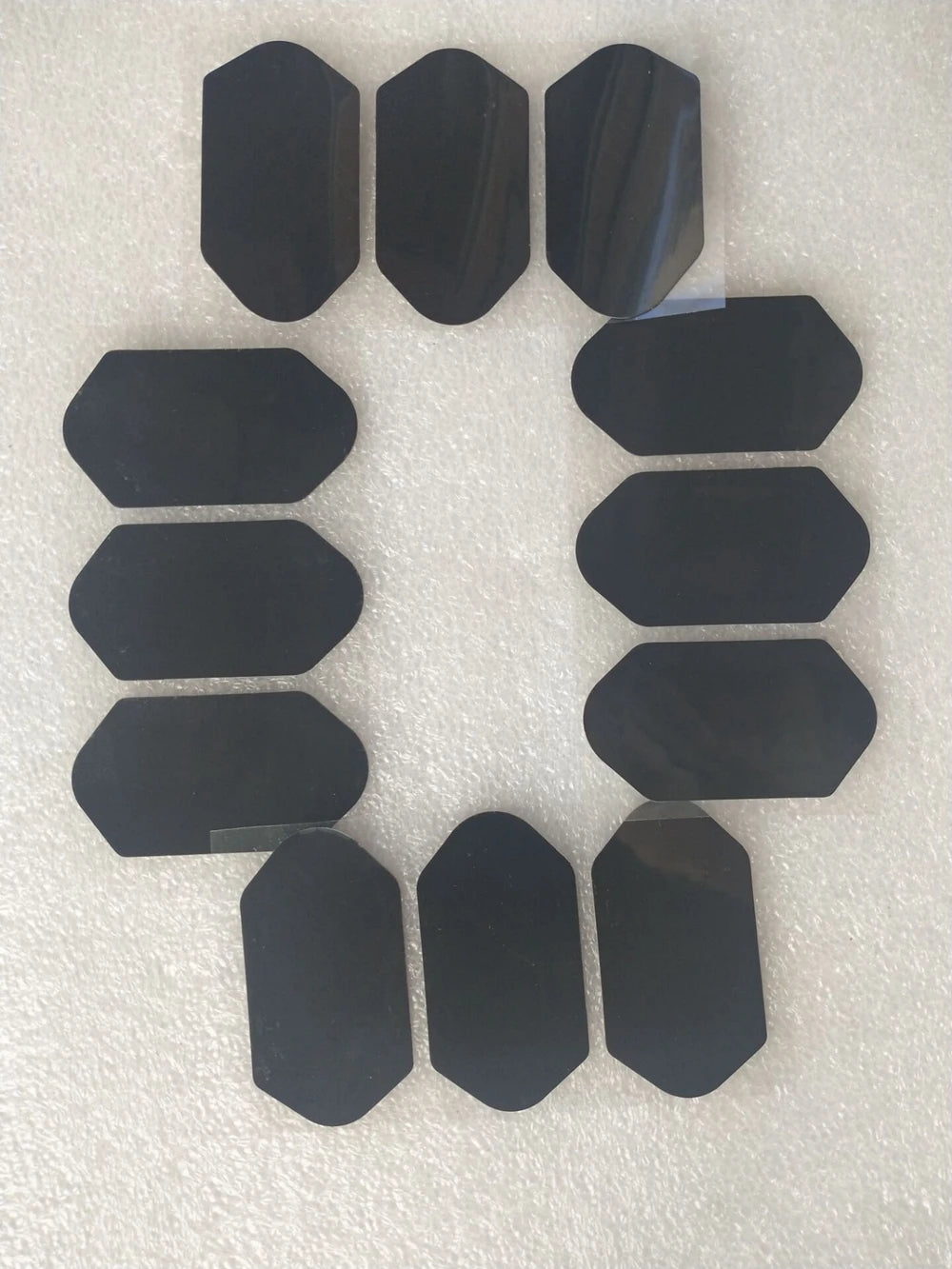 Ten black, hexagonal adhesive patches for repairing fabric or vinyl items, arranged on a white protective backing.