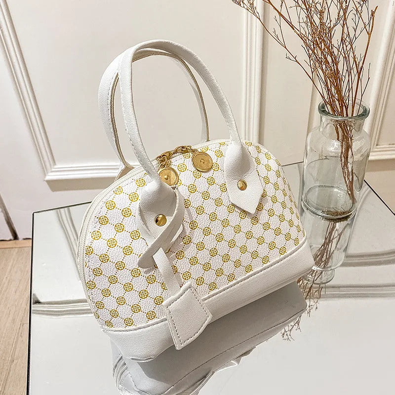 White shell handbag with gold geometric pattern, zipper closure, and dual top handles. Stylish daily designer bag.