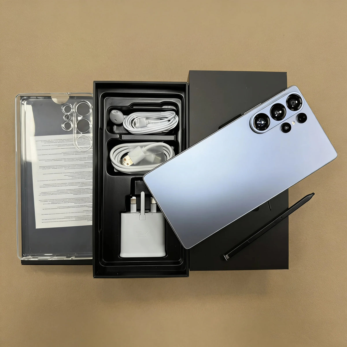 Unlocked smartphone with light gray back, shown beside open box with charging accessories