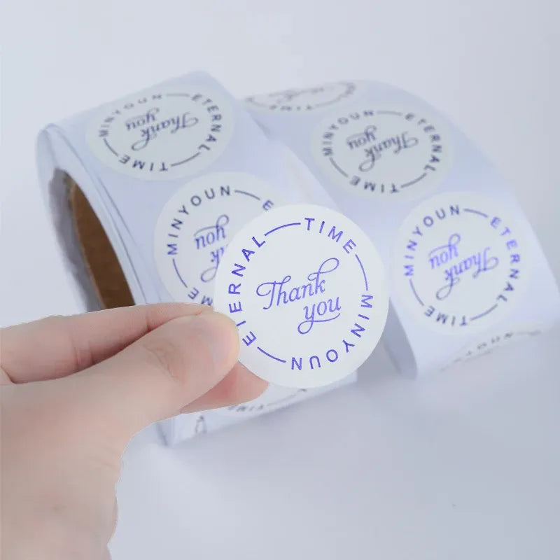 Circular “Thank you” label stickers with blue script on clear backing sheet