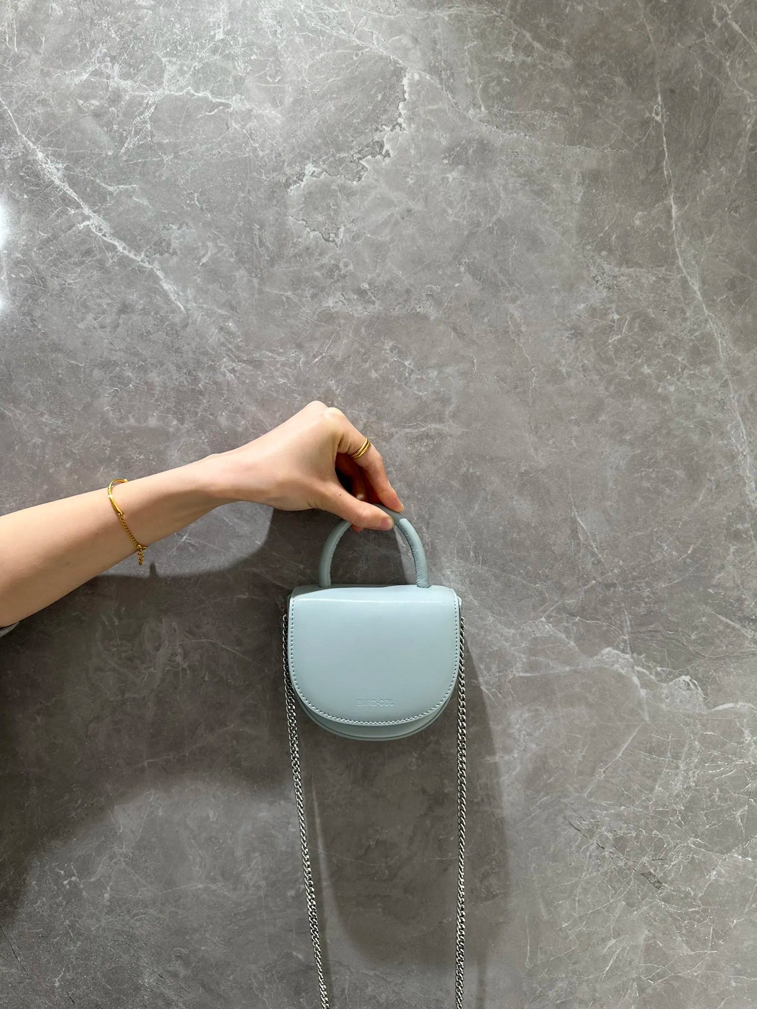 Light blue cowhide leather evening clutch with top handle and silver chain strap for weddings and parties.