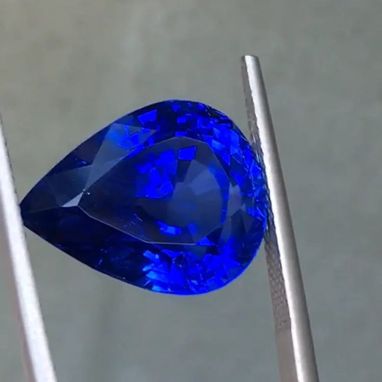 Royal blue pear-cut sapphire loose stone beside metal rod