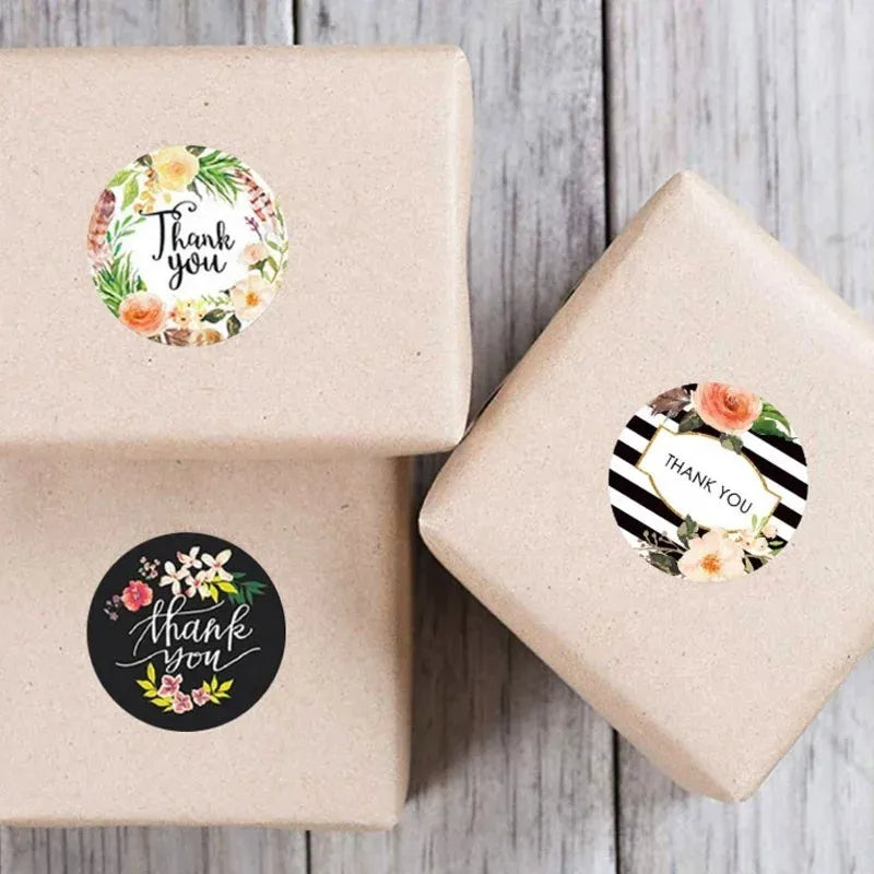 Round thank you stickers with floral wreaths on kraft gift boxes