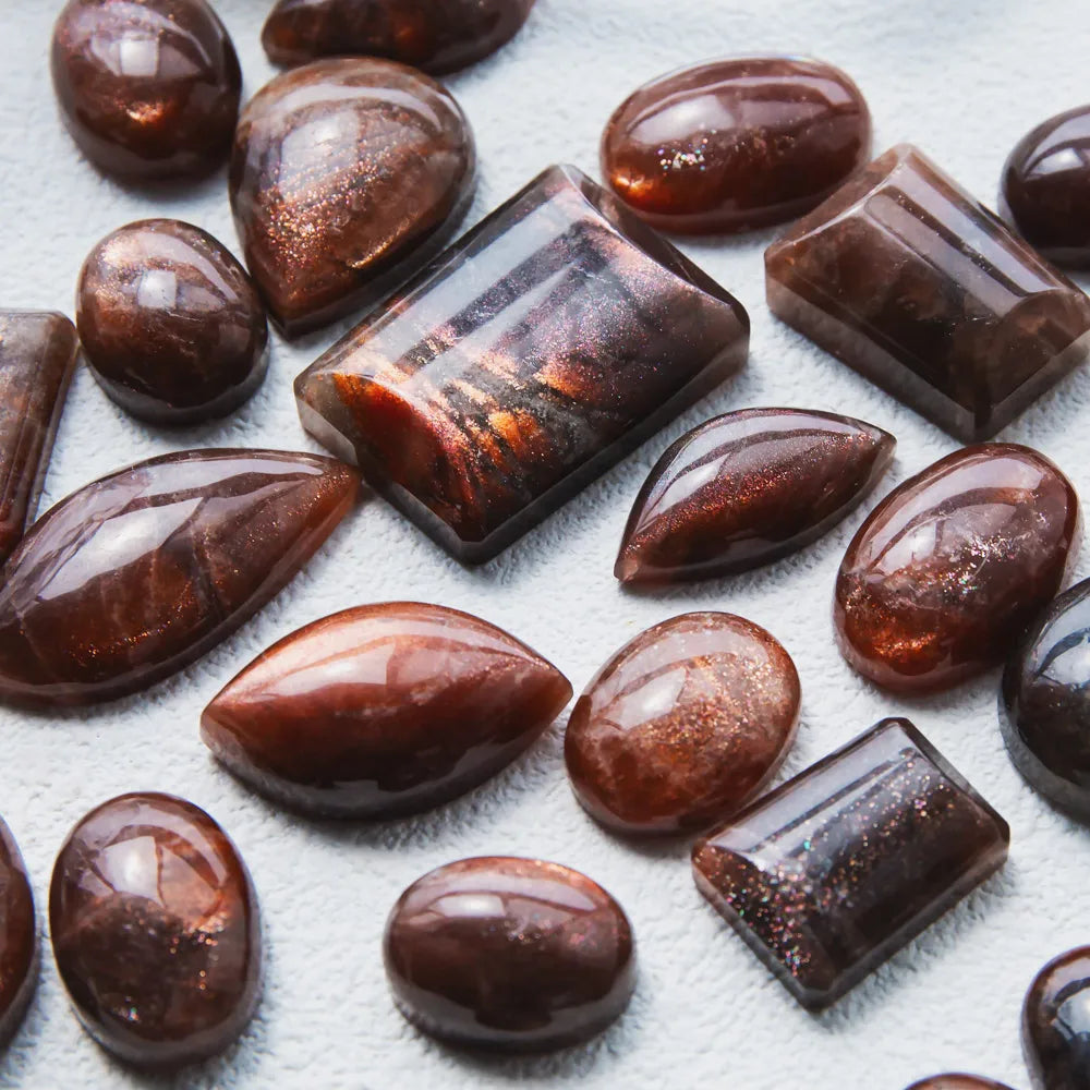 Assorted golden sunstone cabochons with glossy banded dark red and orange highlights