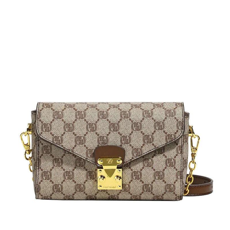 Monogram heritage cowhide leather envelope crossbody bag with gold hardware and shoulder strap.