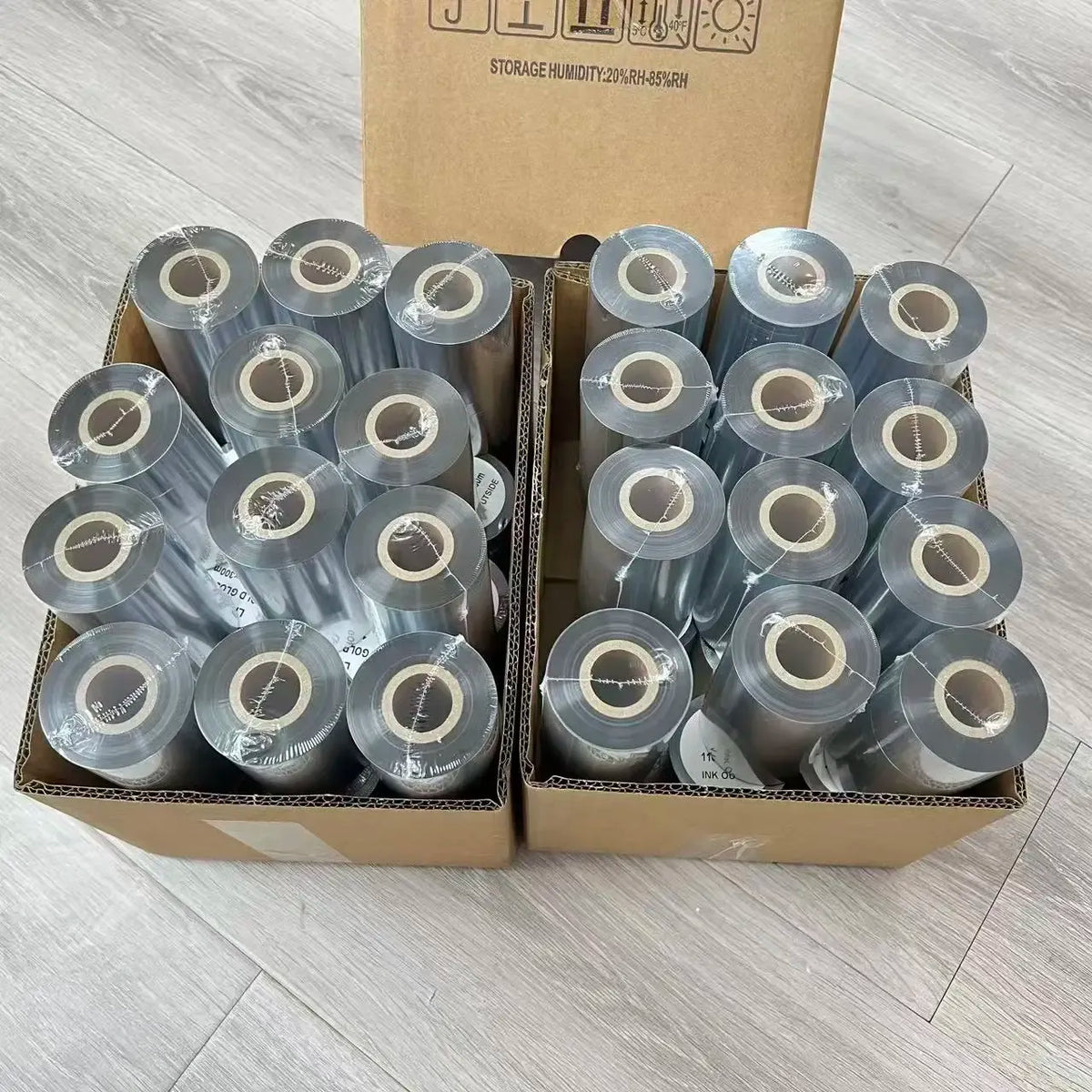 Box of thermal transfer ribbon rolls with silver-gray cores and protective outer film