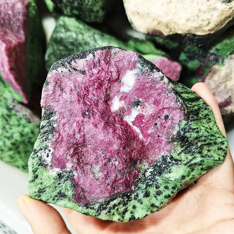 Large rough red and green quartz stone with speckled white patches, held in hand