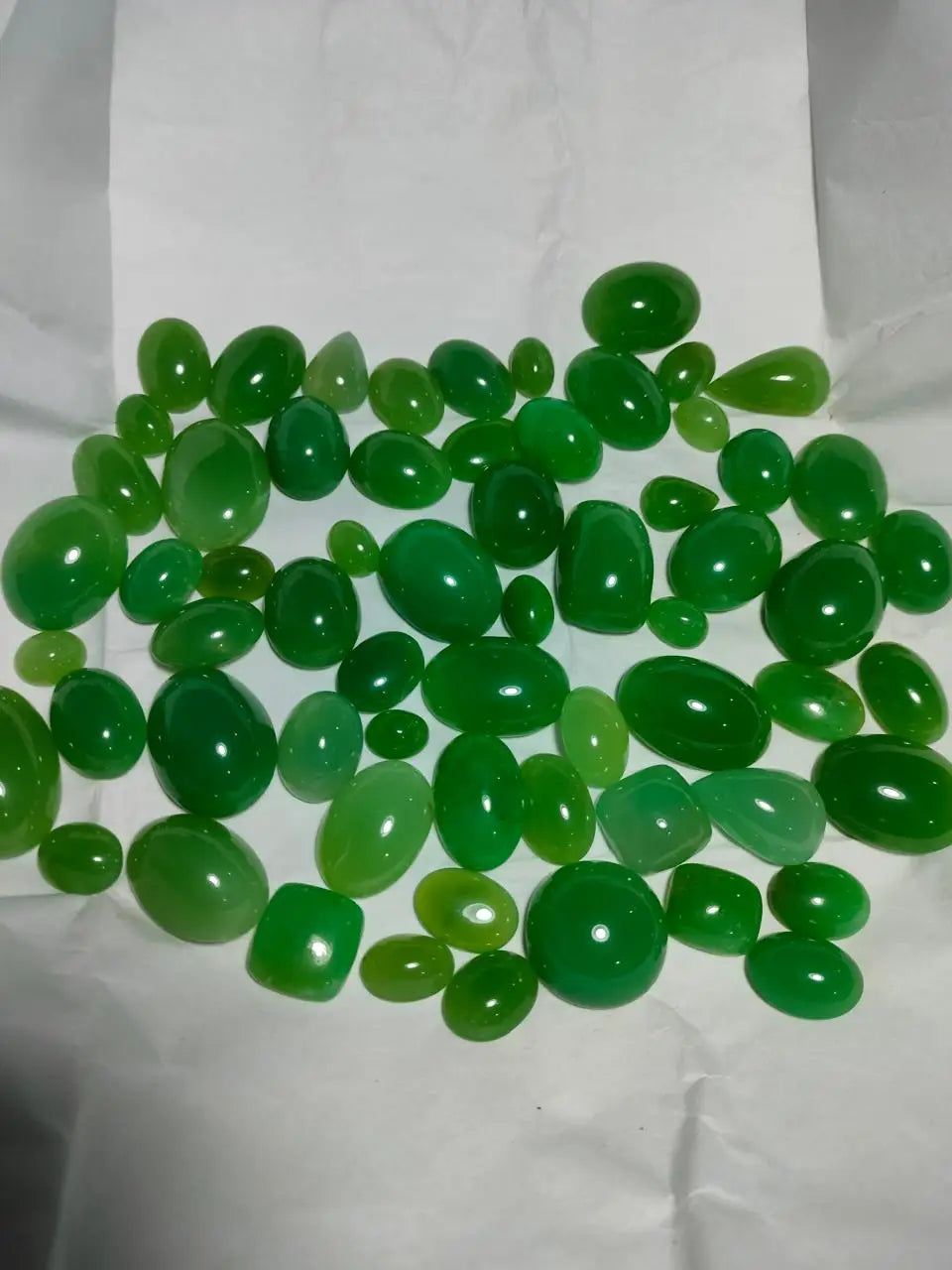 Pile of green polished cabochon gemstone pear cuts