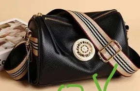 Black genuine leather designer handbag, barrel shape, gold medallion hardware, and striped wide shoulder strap.
