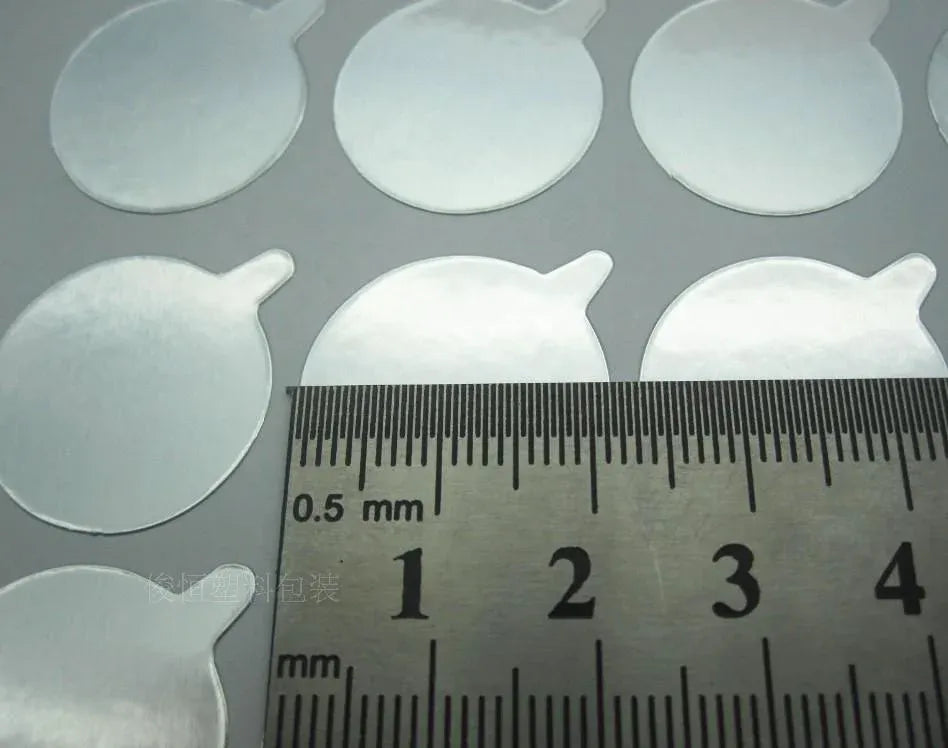 Round aluminum seal stickers with ruler scale, showing small thickness detail
