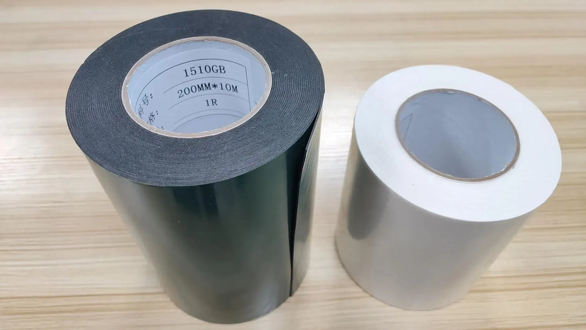 Double-sided carpet tape rolls, dark gray and white on cardboard cores