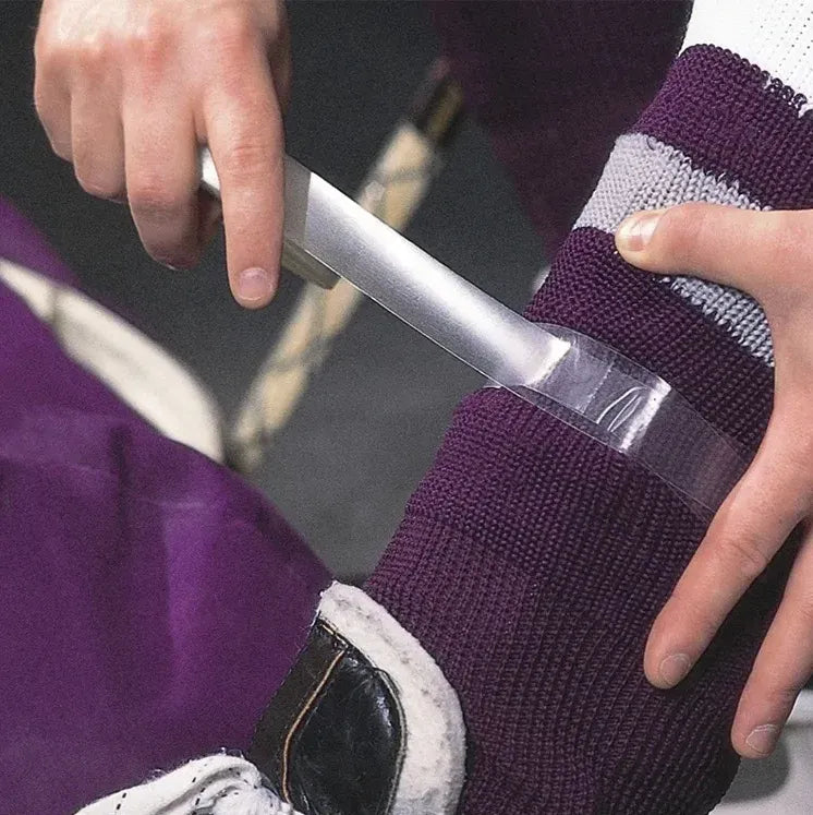 Tape being wrapped around a shin pad on an ice hockey sock