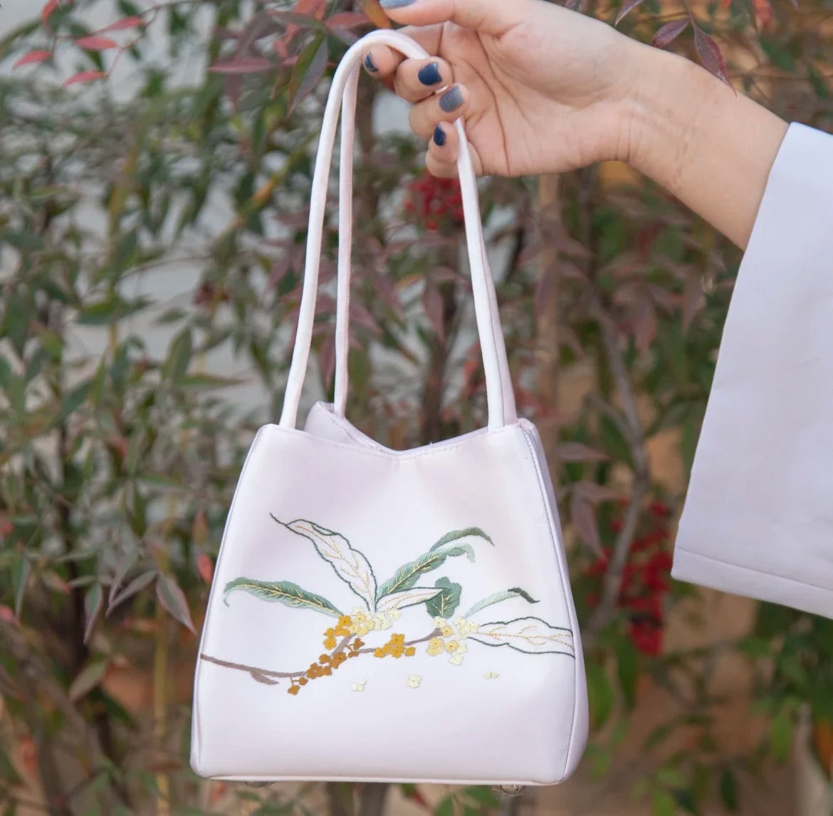 Pale pink silk shoulder bag with traditional Chinese floral Su embroidery and thin, elegant carrying straps.