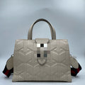 Elegant white quilted leather designer handbag with geometric stitching, dual handles, and striped shoulder strap.