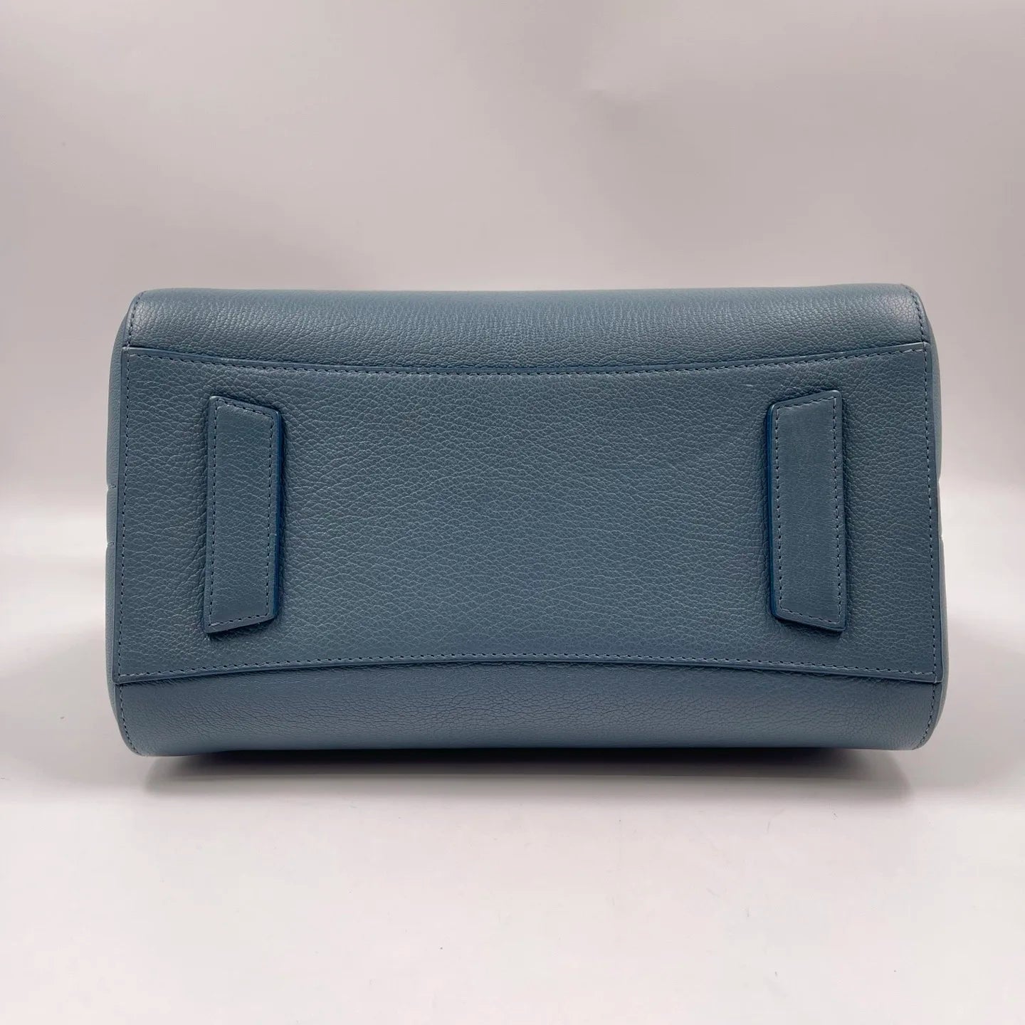 Blue pebbled genuine leather designer handbag, rectangular base with structured side tabs. Classic luxury tote style.