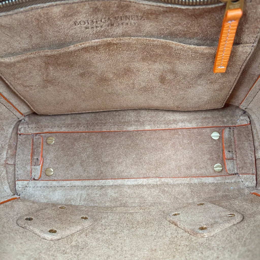 Interior of luxury Bottega Veneta genuine leather designer handbag, tan suede lining with orange trim and gold hardware.