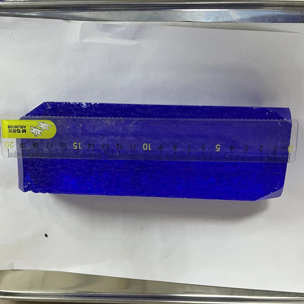 Blue synthetic hydrothermal crystal block in plastic sleeve with measuring tape length.