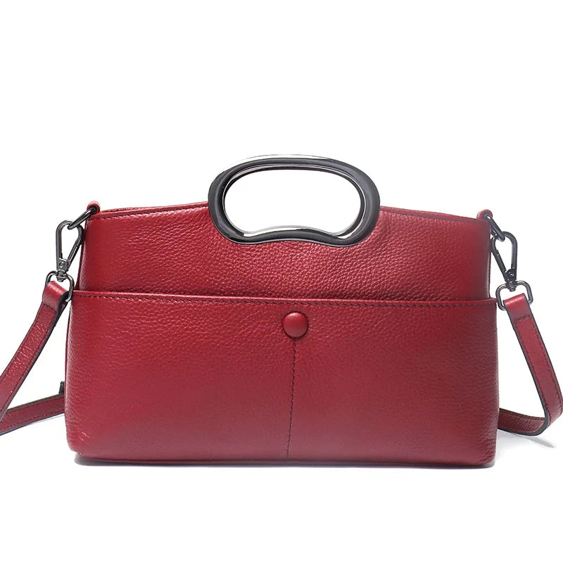 Red pebbled PU leather designer crossbody bag with a unique metallic oval top handle and detachable shoulder strap.