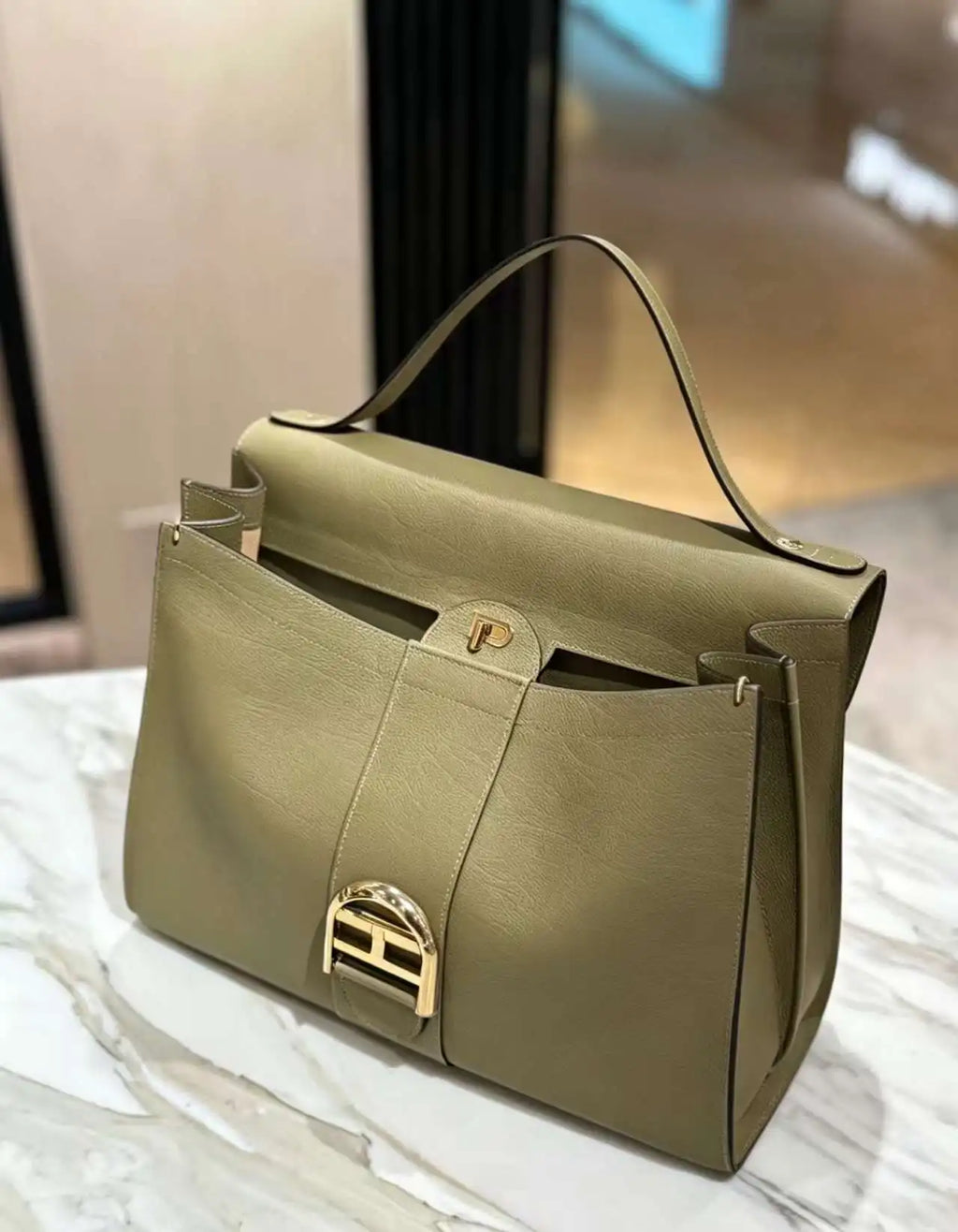 Olive green leather luxury tote handbag with gold H-shaped hardware and structured shoulder strap design.