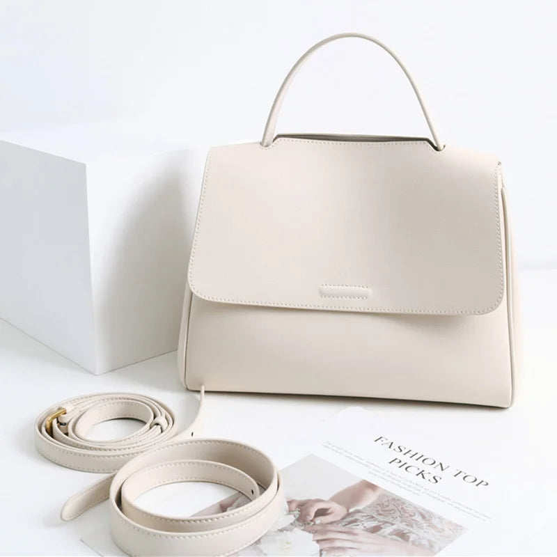 Minimalist cream leather designer handbag, Korean style messenger bag with top handle and adjustable shoulder strap.