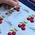 Vinyl die-cut sticker sheet with red cherries and green leaves, plus script outlines